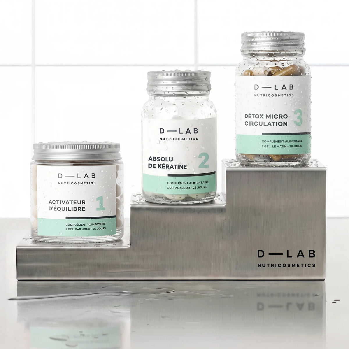 Routine Masse-Capillaire D-LAB cure 1 mois, les trois pots Activateur d'Équilibre, Absolu de Kératine et Détox Micro Circulation disposés en escalier sur socles inox